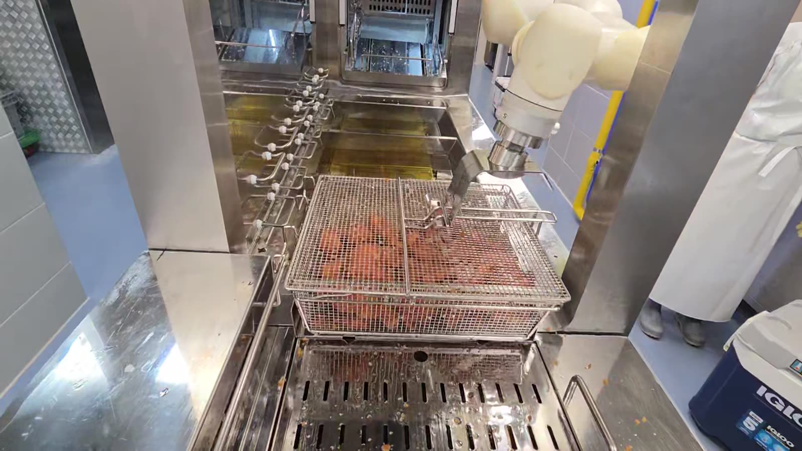 A basket of finished fried chicken lifted onto the discharge grate