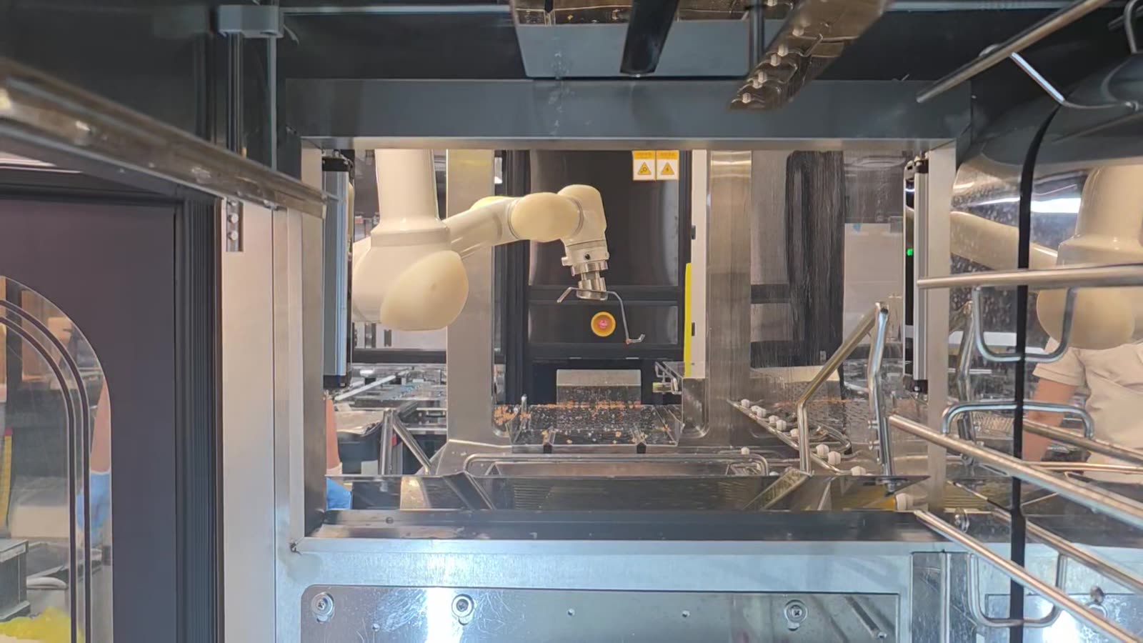 The 6-axis robot arm working behind the safety frame